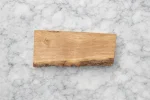 Handcrafted sweet chestnut board with natural bark edge and smooth grain, displayed on marble background by Chonky Wonky Wood, Ipswich Suffolk.